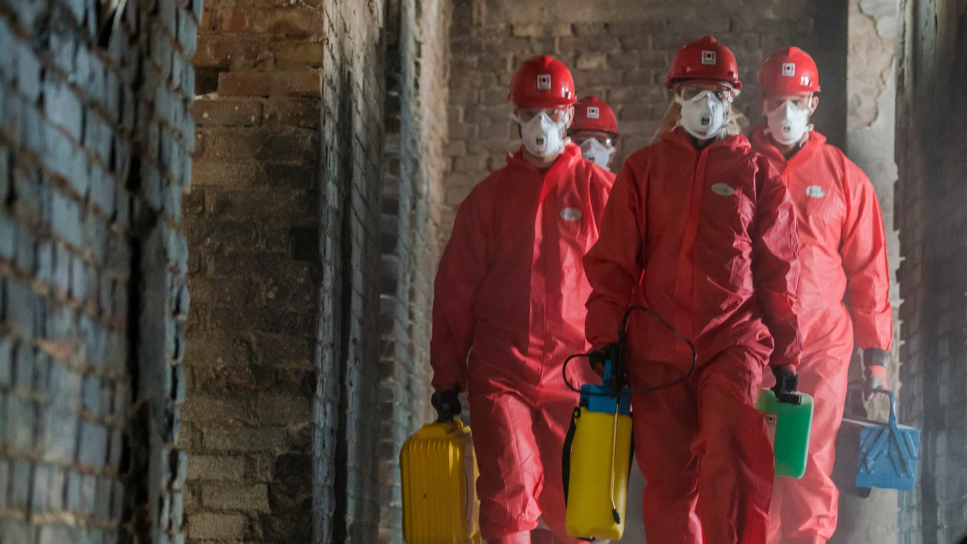 Male-employees-in-red-PPE-suits-walking-in-a-damaged-structure