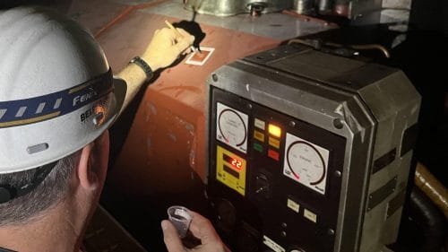 BELFOR worker testing a substance on the surface of a machine in a ship