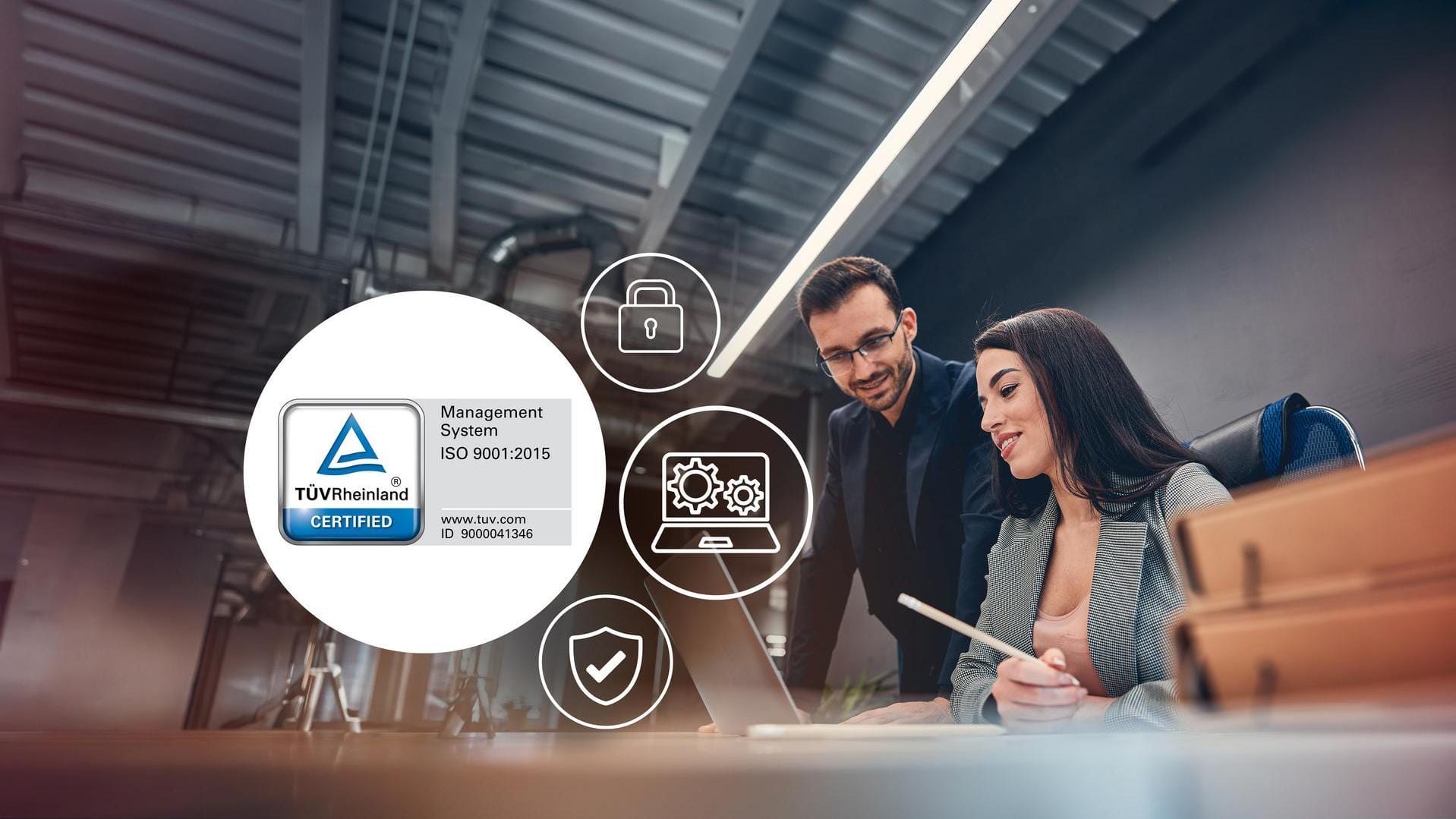 A man and a women looking at a laptop screen while being in an office